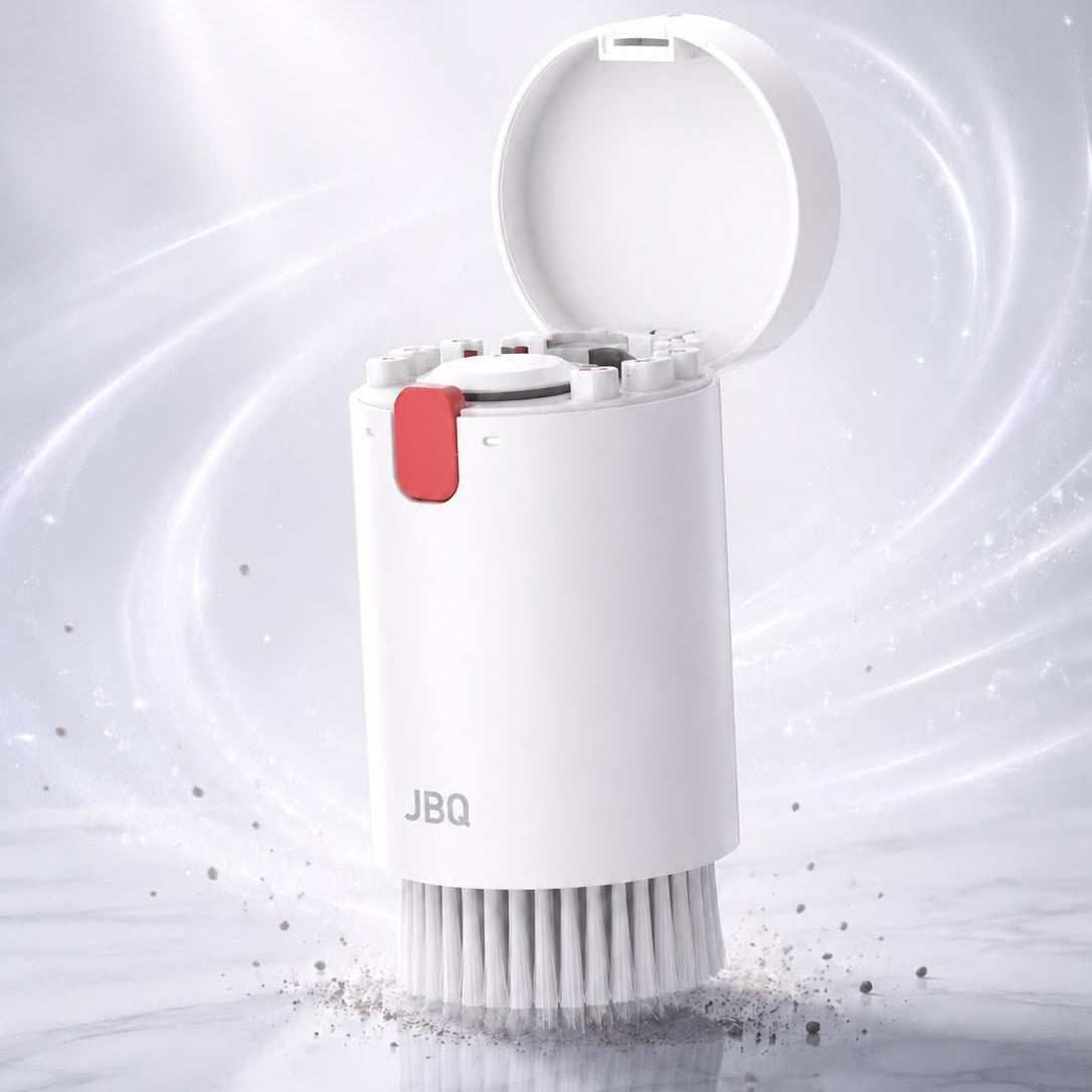 A white cylindrical cleaning brush with an open lid, shown on a light marble-like surface with a soft white and gray background and swirling light effects. The brush has a small red tab and the brand name JBQ printed on the front.
