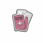 A travel-themed enamel pin depicting a pink passport with a white airplane icon and the word 'PASSPORT' in black, layered behind two white boarding passes with black outlines, on a solid white background.