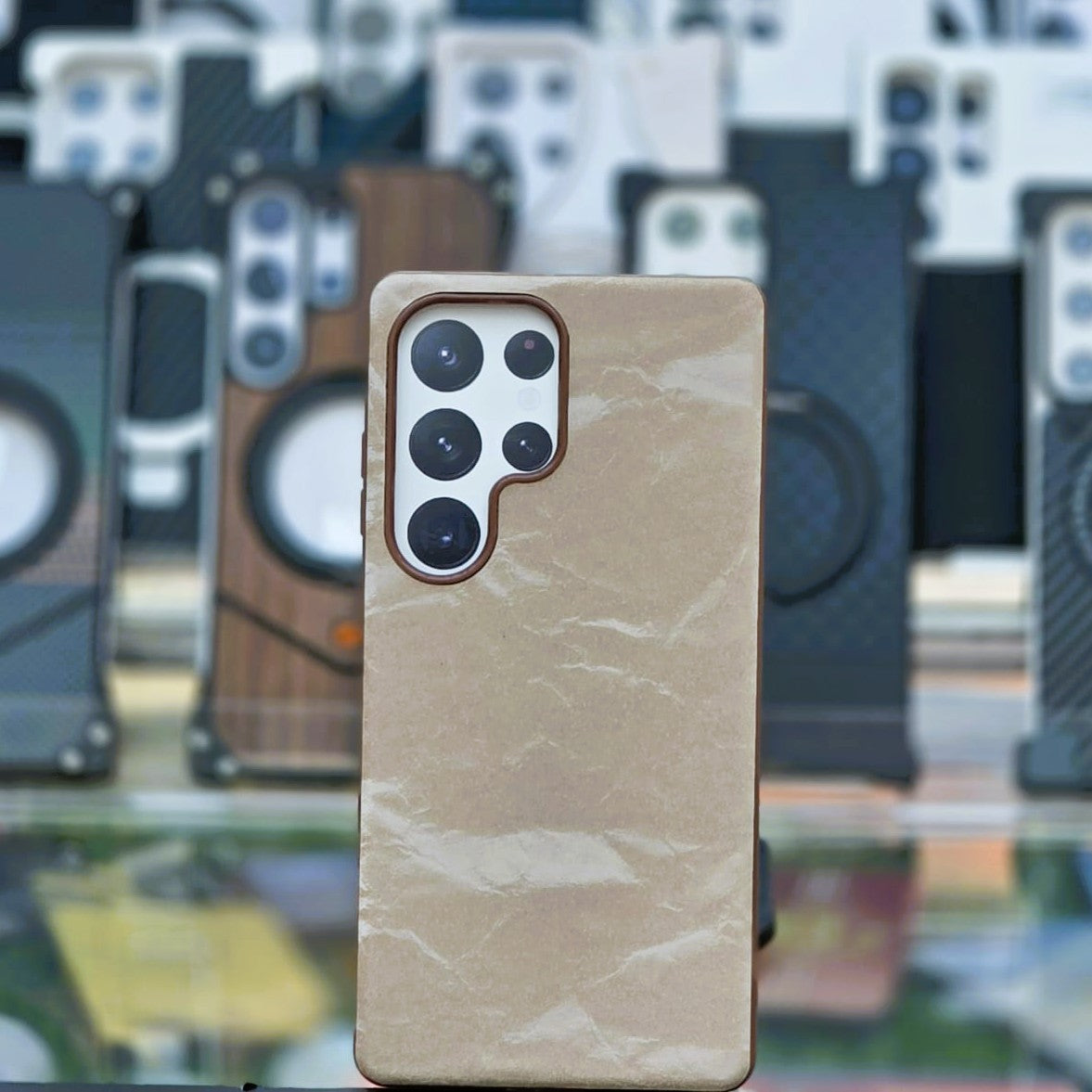 Beige marble-patterned phone case on a blurred background of various phone cases.