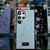 Glittery phone case with brand logo against a blurred background of other phone cases.