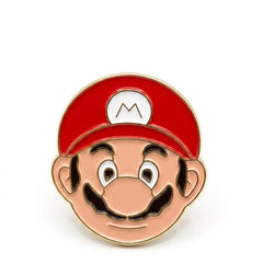 An enamel pin shaped like Mario's face, featuring his iconic red cap with a white 'M' logo, peach skin, black mustache, and gold-tone metal outlines, set against a plain white background.