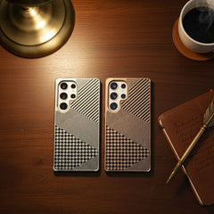 Two phone cases with geometric patterns on a wooden surface with a lamp and notebook.