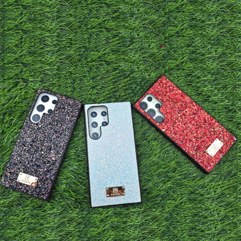 Three phone cases in black, silver, and red on a grassy surface