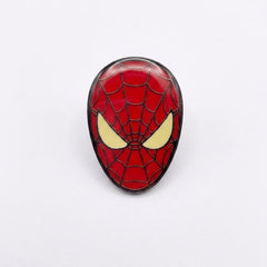 A Spider-Man themed oval enamel pin featuring the iconic red and black web pattern with yellow eyes, set against a plain white background.